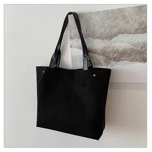 Macro detail of black suede texture and glossy leather strap on minimalist tote bag