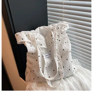 Close-up of white pleated tote bag with black floral print and Fashion Bag woven label