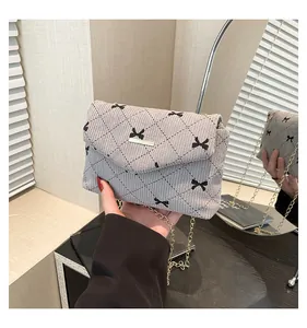 Detail of grey corduroy crossbody bag with diamond stitching and golden chain strap