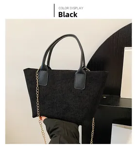 Detail of black corduroy tote bag showing vertical texture and gold chain strap