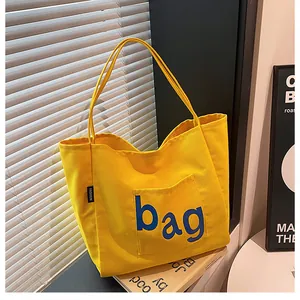 Gros plan d'un sac cabas en toile jaune avec imprimé bleu et étiquette mode tissée