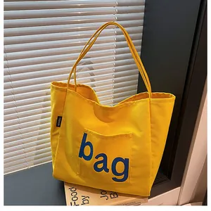 Détail d'un sac cabas en toile jaune vif avec inscription artistique bleue marine bag