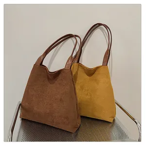 Detail of large suede tote bags in brown and yellow colors for daily commuting use