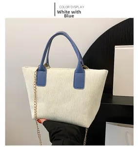 Detail view of white corduroy tote bag with contrasting blue handles and gold chain strap