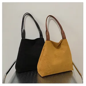 Detail of matte suede tote bags in black and yellow colors on a metal chair