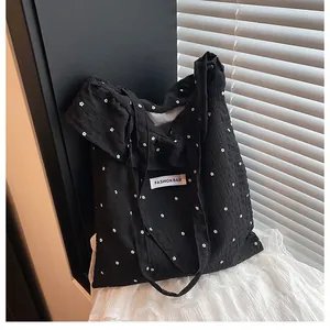 Detail of black tote bag featuring textured bubble fabric and white floral embroidery
