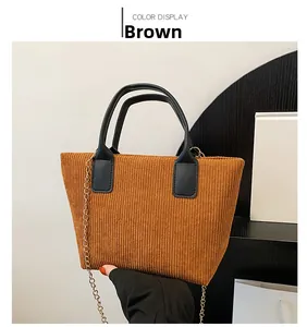 Detailed close-up of brown corduroy tote texture with black handle and gold chain