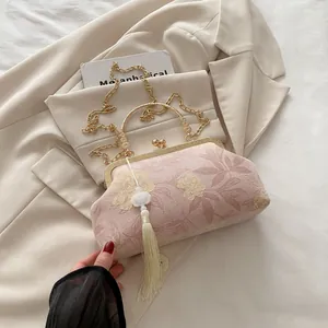 Detail of pink floral brocade shell bag with gold metal frame and long tassel pendant