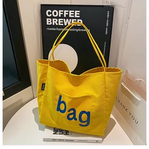 Détail d'un sac fourre-tout en toile jaune avec imprimé bleu sur table blanche