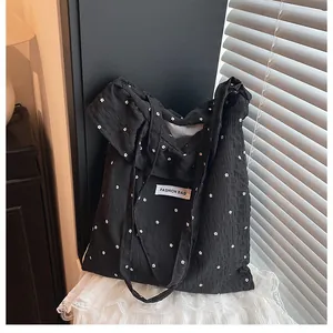 Close-up of black floral tote bag with wrinkled texture and Fashion Bag woven label