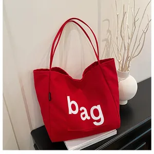 Gros plan détaillé d'un sac cabas en toile rouge avec l'inscription blanche bag sur la poche