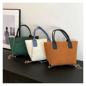 Close-up of corduroy tote bags in green, beige and brown with golden chain straps
