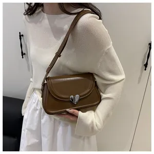 Dettaglio della borsa a tracolla quadrata marrone con chiusura in metallo a forma di cuore