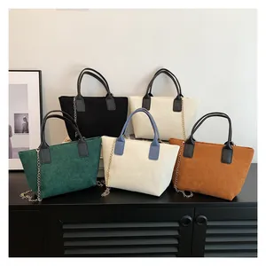 Collection of corduroy tote bags in multiple colors displayed on a wooden cabinet