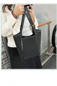 Détail d'un grand sac cabas en nylon noir avec bordures en cuir et boucles dorées chic