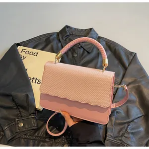 Détail du sac sous l'aisselle rose tissé avec bords ondulés et poignée métallique