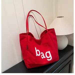 Vue détaillée d'un sac cabas en toile rouge avec étiquette mode et poche extérieure