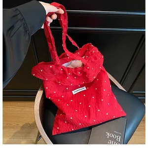 Detail of red floral tote bag with wrinkled fabric texture and white flower embroidery