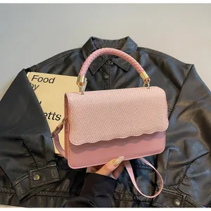 Gros plan du sac rose avec rabat à texture tissée et détails de bord festonné