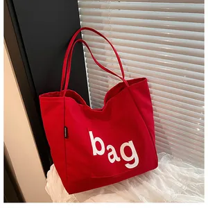 Détail du sac cabas en toile rouge avec grande poche avant et lettrage blanc imprimé