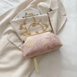 Detailed embroidery on pink cheongsam bag with golden handle and cream tassel