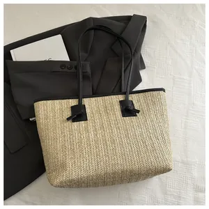 Detail of hand-woven straw tote bag with black leather handles and knot accents