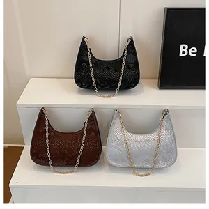 Dettaglio di tre borse hobo in nero, marrone e argento con texture in pelle di serpente