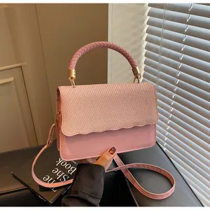Vue détaillée de la poignée tisseé rose et du rabat à motifs ondulés de ce sac à bandoulière