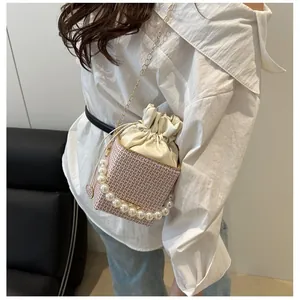 Rosa-weiße Monogramm-Eimertasche mit Perlengriff und Metallkette am Model getragen