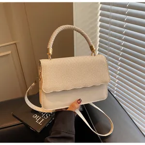 Détail de la texture tissée beige et de la bordure ondulée sur le rabat du sac porté épaule