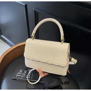 Détail du sac à bandoulière blanc crème avec rabat en sergé et design à bords ondulés
