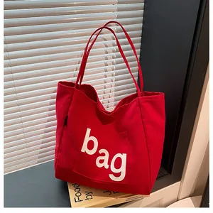 Gros plan d'un sac cabas rouge en toile avec lettrage posé sur le bord d'une fenêtre