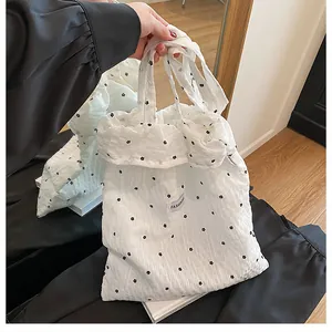 Detailed macro view of white textured tote bag with small black flower embroidery