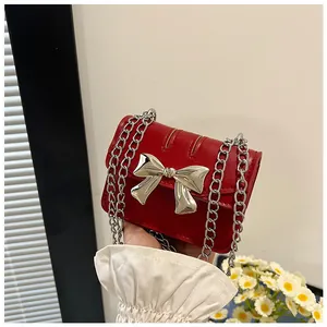 Detailed shot of a red patent leather mini bag with a silver bow and metal chain strap