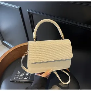 Détail du sac à main beige tressé avec bord ondulé et boucle en métal doré chic