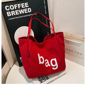 Gros plan sur un grand sac fourre-tout en toile rouge avec logo blanc et étiquette mode
