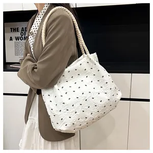 Gros plan du sac fourre-tout blanc avec motifs nœuds noirs et texture de tissu plissé