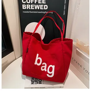 Détail du sac fourre-tout en toile rouge avec poche frontale et texte bag blanc
