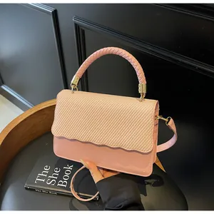 Détail du sac à bandoulière rose clair avec texture tissée et bordure ondulée chic