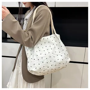 Détail du sac plissé blanc avec motifs de papillons noirs et anse en corde de coton
