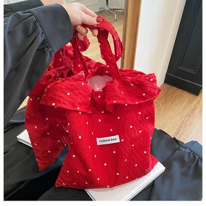 Detailed close-up of red floral fabric tote bag with ruffle trim and soft texture