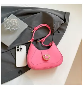 Detail of bright pink suede underarm bag with gold D-ring buckle and knotted handle