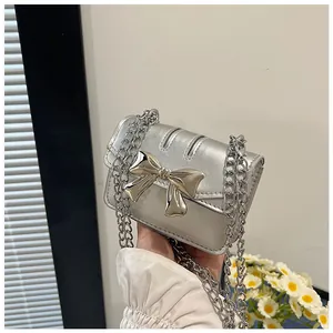 Detail of silver metallic mini crossbody bag with oversized bow and chain strap