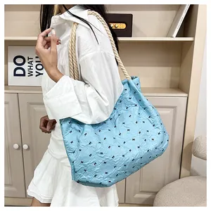 Détail du sac cabas plissé bleu clair avec broderie nœud et anse en corde sur modèle