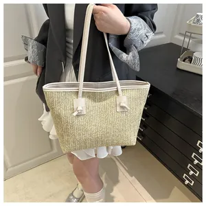 Detailed shot of beige straw woven tote bag with leather straps and decorative knots