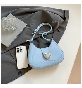 Detail of light blue suede shoulder bag with silver D-buckle and decorative knot