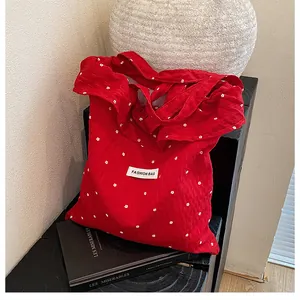 Close-up of red floral tote bag with white flower pattern and Fashion Bag woven label