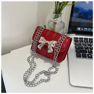 Detail of red PU leather mini crossbody bag with silver bow buckle and chain strap