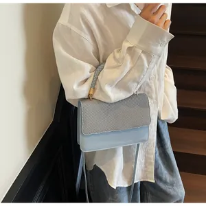 Détail du sac bleu clair avec rabat tissé, bords ondulés et poignée tressée chic