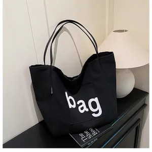 Détail du sac fourre-tout en toile noire avec imprimé bag blanc et étiquette mode